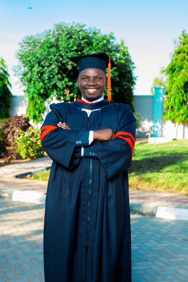 A person in academic regalia pictured on the ACTS grounds.